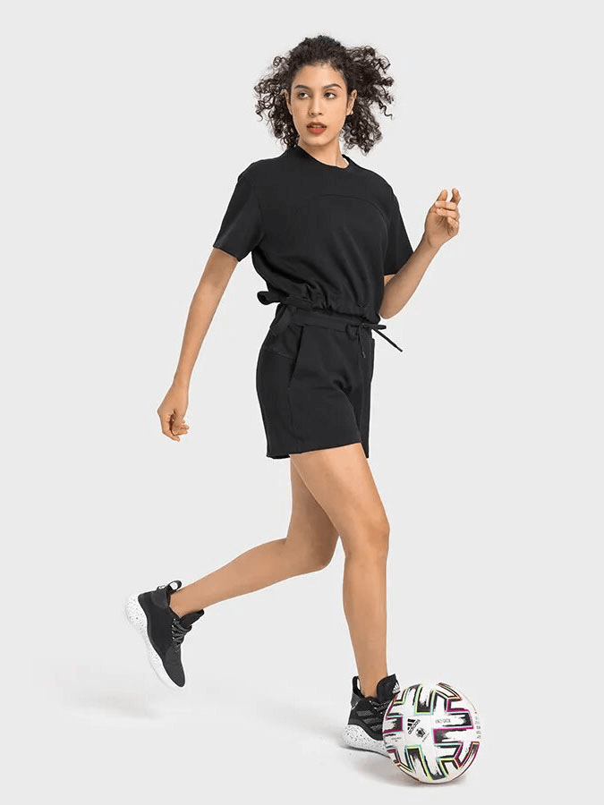 Woman wearing black sports short sleeves crop T-shirt with adjustable hem, playing soccer; perfect for running, yoga, and dance.